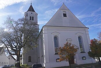 Rennertshofen St. Johannes der Täufer Außenansicht Kirche mit Turm und Bäumen im Vordergrund bei sonnigem Himmel und blauem Hintergrund.